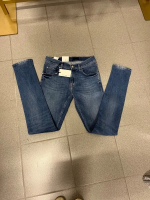 Tiger of Sweden slimmade jeans blå W30 L34 - Snygga blå jeans från Tiger of Sweden med tight passform och smal fot. Klassisk femficksmodell med läderpatch bak och diskreta detaljer. Perfekta för dig som gillar en stilren och modern look.