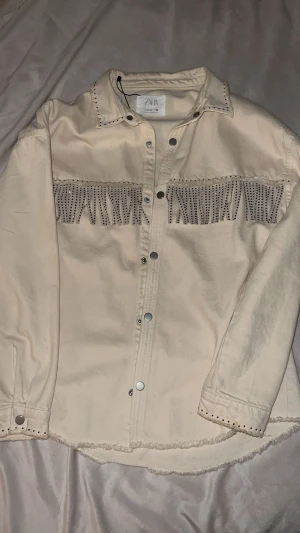 Tunnjacka  -beige /sand cream  - Snygg tunn jacka/skjorta i beige/sand/cream med fransdetaljer. Perfekt för dig som gillar neutrala färger och vill matcha med nästan vilken outfit som helst eller bryta av med den som en stilfull detalj. Jackan har bra material, perfekt längd som täcker ner till ryggen, inga fläckar och tål att användas ofta.