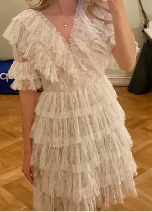 Vit spetsklänning med volanger - By Malina Sky dress vit, använd 1 gång,  köpt för nypris 2800 kr, har en defekt (bild 6 och 7) som inte har någon betydelse, kom med prisförslag💖 passar storlek 34-36