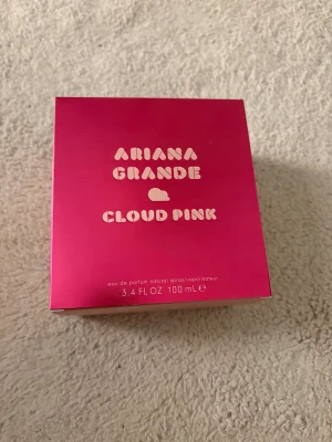 Ariana Grande Cloud Pink 100ml - Trendig parfym med unik molnflaska från Ariana Grande. Cloud Pink, 100 ml eau de parfum – perfekt för dig som vill sticka ut med en ikonisk doft och snygg design på hyllan. Helt oanvänd!