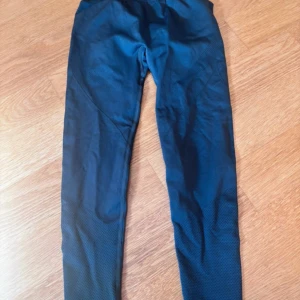 Svart gråa leggings  - Säljer ett par svart gråa leggings med scrunch-detalj bak och diskret mönstrad struktur på benen. De har tight passform och är gjorda i ett stretchigt syntetmaterial, perfekta för träning eller chill. Snygg design som framhäver formerna.