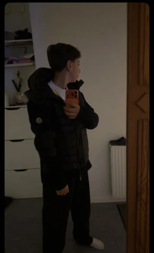 Svart Moncler pufferjacka med huva - Svart pufferjacka från Moncler med stickade ärmar och vadderad kropp. Jackan har huva, dragkedja framtill, två fickor med knappar och Moncler-logga på ärmen. Snygg och stilren design som passar perfekt till höst och vinter.