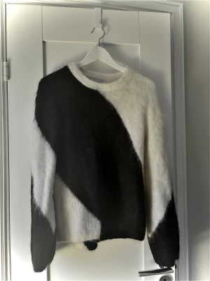 Svartvit stickad tröja & Other Stories - Säljer en fluffig stickad tröja från & Other Stories i storlek XS. Tröjan har ett coolt svartvitt mönster med breda diagonala ränder och rund hals. Materialet är mjukt och ger en mysig känsla, perfekt för att hålla sig varm under kyliga dagar.