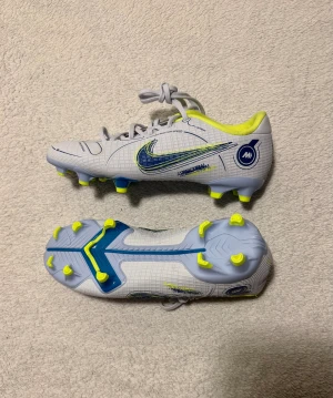 Nike Mercurial Vapor Fotbollsskor Strlk 34 - Nike Mercurial Vapor 14 Academy MG fotbollsskor, aldrig använda, supersnygga och i perfekt skick, storlek 34 💕 Vita med blåa och neongula detaljer. Tyvärr följer inte kartongen med, men skorna är helt nya. Originalpris: 799 kr.  Skriv gärna om du undrar något!