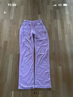 Ljusrosa velourbyxor Juicy Couture XS - Supermjuka ljusrosa velourbyxor från Juicy Couture i storlek XS. Byxorna har resår i midjan, raka ben och fickor både fram och bak med snygga knappar. Perfekta för en chill och trendig look. 