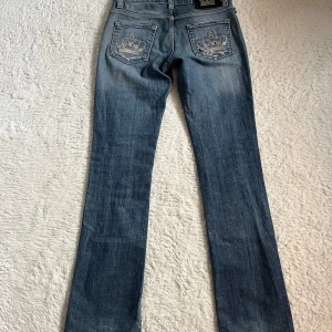 Victoria Beckham jeans - Midjemått 37cm Innerbenslängd ca 82cm  Såå snygga jeans från Victoria Beckham, säljer eftersom de är för små för mig. Lågmidjade och lite bootcut. De är i en snygg mörkblå tvätt och knapparna är silverfärgade. De har även den klassiska kronan på bakfickorna🙌 Tyvärr är det ett hål i ena bakfickan. En söm har även gått upp lite (syns på sista bilden). De är även lite slitna längst ner men det tycker inte jag gör nånting. Supersnygga ändå!  Storlek W38 L32 och jag skulle säga att de sitter som xs