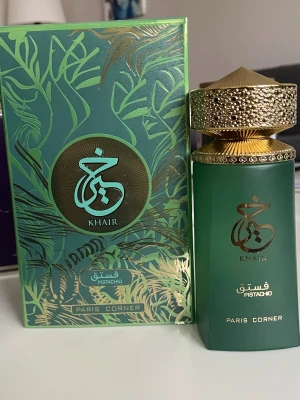 Khair Pistachio Eau de Parfum - Upptäck Khair Pistachio från Paris Corner – en unik parfym i snygg grön flaska. Innehåller bl.a. limonene, linalool, citronellol och geraniol. Volym: 100 ml. Perfekt för dig som vill sticka ut med något annorlunda och trendigt.