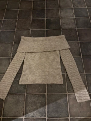Beige ribbad offshoulder stickad tröja H&M - Säljer en beige stickad tröja från H&M i storlek XS. Tröjan har ribbad struktur och en bred offshoulder-krage som ger en snygg och chill vibe. Långärmad och mjuk, perfekt för att hålla sig varm under kyliga dagar.