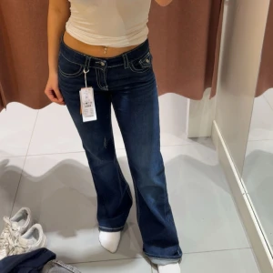 Gina Tricot Young Chunky Low Flare Jeans - Gina tricot young mörkblå bootcut jeans med markerade vita sömmar och snygga fickdetaljer där bak💞