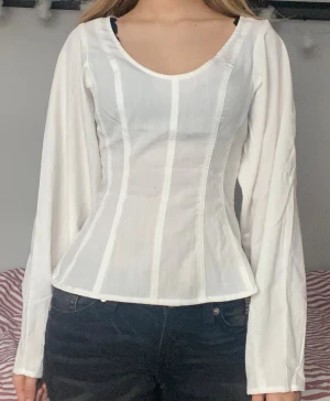 V- ringad blus - Säljer en superfin vit blus med vida ärmar och v-ringning. Den är lite korsettinspirerad och såå fin 💗Hör gärna av dig vid frågor