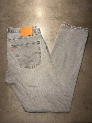 Archive Jeans Levis - Säljer ett par riktigt snygga grå/svarta Levis Jeans 501. De har en rak passform och lägger sig snyggt över skorna. Storlek:  W33 L30. Skriv vid frågor eller kom med bud!