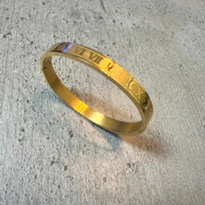 Guldfärgat armband med romerska siffror - Coolt armband i guldfärg med ingraverade romerska siffror runt hela bandet. Stilren och tidlös design som ger en lyxig känsla till din outfit. Perfekt accessoar för dig som gillar detaljer med en twist. Steinless steel som tappar aldrig färg 