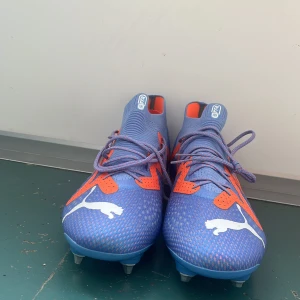 Blå-orange Puma fotbollsskor strl 43 - Helt nya blå-orange Elit Puma fotbollsskor. De har metal dubbar för och få det bästa greppet på en fotbollsplan som möjligt