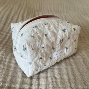 Blommig necessär - Storlek S (12,5x8,5x8,5cm) | Quiltad necessär i vitt bomullstyg med små blå blommor och med rosa innertyg. Perfekt för skolväskan eller andra väskor on the go🦋| Handsydd med min egen label