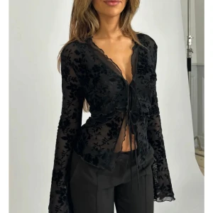 Svart topp från Venderbys - Säljer en svart transparent blus från Venderbys med blommigt mönster i sammet. Använd endast 1 gång så den är i jätte fint skick😍