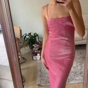 Balklänning - Superfin rosa balklänning med tunna band i glansigt tyg med broderade blommor med stenar i. Klänningen går ner till golvet på mig som är 173 cm. Kan mötas i Stockholm, alternativt att köparen står för frakten