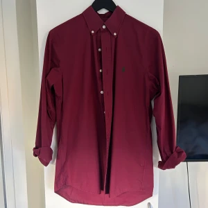 Vinröd skjorta från Ralph Lauren - Vinröd skjorta från Ralph Lauren i klassisk passform. Jättefint skick! Skjortan är tillverkad i bomull. Perfekt för dig som gillar stilrena och tidlösa plagg. Checka även min profil för andra Ralph lauren skjortor och dondup jeans!
