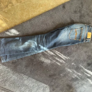 Blå jeans från Nudie Jeans, modell Thin Finn - Säljer ett par klassiska blå jeans från Nudie Jeans, modell Thin Finn. Riktig snygga och sköna jeans. Hade inte sålt de om jag kunnat förutsatt ha dem. Fin tvätt. Byxorna är nedsydda från 34 och passar mig som har 32