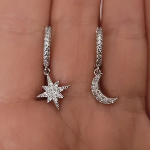  Helt nya Stjärn- och månörhängen i silver -  Helt nya Snygga örhängen i äkta 925 silver med glittriga stenar. Ena örhänget har en stjärna och det andra en måne, båda täckta av små gnistrande stenar. Perfekt för dig som gillar unika detaljer och vill sticka ut.