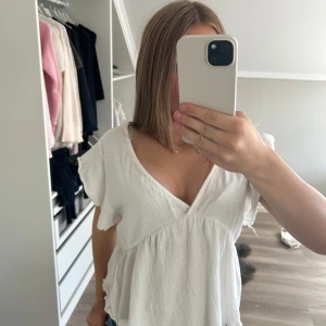 Vit blus med volangärm från 157 - Supersöt vit blus från 157 med v-ringning, volangärmar och knyt i nacken. Den är i bra skick och använd ca två gånger pga att den är för stor. Den är i storlek S och är från lager 157❤️