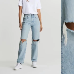Ljusblå ripped straight jeans - Säljer ett par ljusblå jeans med raka ben och stora slitningar vid knäna. Jeansen har hög midja och klassisk femficksdesign. Perfekta för en avslappnad och trendig look.