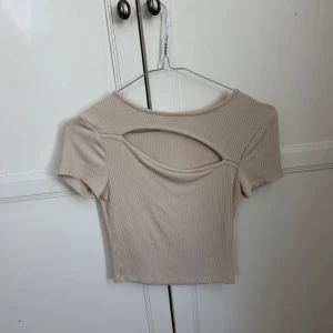 Beige top - Top med öppning från Gina tricot. Toppen är xxs men väldigt stretchig. Fungerar perfekt som magtröja. 