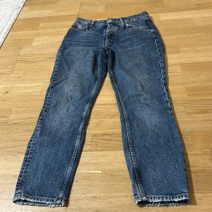 Blå raka jeans med knappar - Klassiska blå jeans från Perfect Jeans med raka ben och hög midja. Jeansen har knappgylf, fem fickor och slitna detaljer vid bensluten. Tillverkade i robust denim med snygga kontrastsömmar. Perfekta för en avslappnad och cool look.