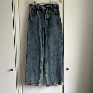 wide jeans  - blå tvättade jeans från Boohoo med hög midja och vida ben. Unik ”in-och-ut” design vid midjan vilket märks på de första knapparna. Perfekta för dig som gillar en avslappnad och trendig look med unika detaljer. Aldrig använda.