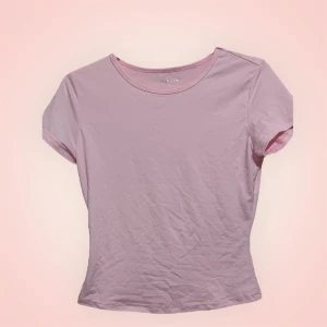 Ljusrosa t-shirt  - Enkel och stilren ljusrosa t-shirt i mjuk bomull. Modellen är kortärmad med rund halsringning och har en figurnära passform. Perfekt att matcha med jeans eller kjol för en clean look.