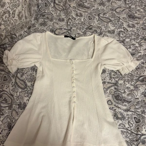 Vit blus med puffärm från BikBok - Supersöt vit blus från BikBok med puffiga korta ärmar och knappar framtill. Knappt använd!!