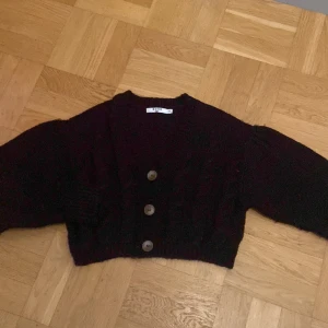 Svart stickad kofta från NA-KD - Mysig svart stickad kofta från NA-KD i storlek S/M. Koftan är croppad med grovstickat mönster, v-ringning och stora knappar framtill 🥰