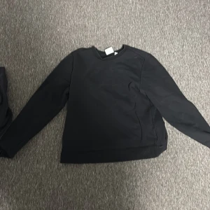 Svart sweatshirt från Andy by Frank Dandy - En stilren svart sweatshirt från Andy by Frank Dandy i storlek S. Tröjan har rund halsringning, långa ärmar och är tillverkad i mjuk bomull. Ni står för frakten!