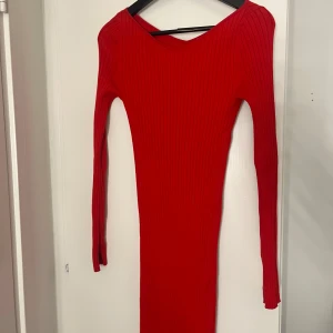 Röd ribbad långklänning - Snygg röd långklänning med ribbad struktur och v-ringad hals. Klänningen har långärmade smala ärmar och är figurnära i modellen. Perfekt för dig som gillar en enkel men ändå iögonfallande look. Materialet känns mjukt och stretchigt.
