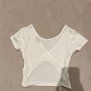 Vit omlottopp från River Island - Säljer en vit omlottopp från River Island i storlek L. Toppen har korta ärmar, croppad passform och snygg omlottdetalj framtill. Tillverkad i ett mjukt och stretchigt syntetmaterial som sitter skönt på kroppen. Perfekt för dig som gillar stilrena och trendiga plagg.