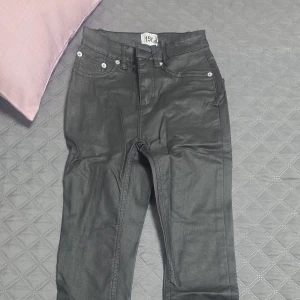 Svarta jeansbyxor med fem fickor - Snygga svarta jeansbyxor med klassisk femficksdesign och silverfärgade nitar. Byxorna har normal passform och stängs med dragkedja och knapp. Perfekta för en stilren och enkel look.