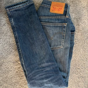 Levi's 501 blå jeans straight fit - Klassiska blå Levi's 501 jeans med rak passform och ikonisk läderpatch bak i midjan. Jeansen är tillverkade i slitstarkt denim och har fem fickor samt knappgylf. Perfekta för dig som gillar tidlös stil och vill ha ett par riktigt schyssta jeans. W29 L30