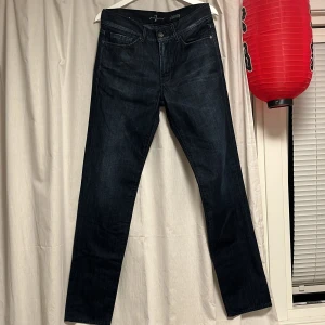 Mörkblå slim jeans från 7 For All Mankind - Snygga mörkblå jeans från 7 For All Mankind i modellen Slimmy. Jeansen har klassisk femficksdesign, smal och rak passform. Perfekta för dig som gillar en stilren och modern look. Cond: 9/10, köpta för ett tag sen men har inte kommit till användning. Pris är ej suttet i sten!!!