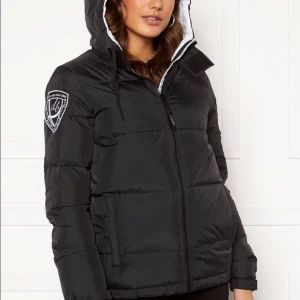 Svart pufferjacka med huva från DBrand - Svart pufferjacka från DBrand med stor huva, dragkedja framtill och röd färg i luvan. Jackan är jätte puffig och perfekt för kalla dagar💗 säljer då jag köpt ny jacka. Skriv för fler bilder eller funderingar💗💗