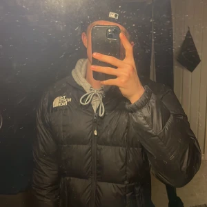 Svart pufferjacka The North Face - Säljer en svart The North Face 1990 Lhotse pufferjacka med logga på bröstet och ryggen. Jackan har dragkedja framtill, hög krage och är riktigt fluffig. Perfekt för kalla dagar när du vill hålla stilen och värmen.