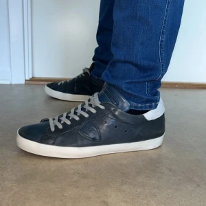 Philippe Model  - Snygga mörkblå sneakers från Philippe Model i skinn med vit detalj på hälen och grå snörning. Klassisk låg modell med vit sula och rund tå. Perfekta till jeans eller shorts för en clean och stilren look. Defekter vid sulan (se på bild 5). Har ni frågor är det bara att höra av sig🙌 nypris : 4000