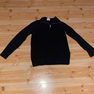 Svart slim fit stickad tröja med half zip - Svart stickad tröja med lång ärm och snygg half zip-dragkedja vid halsen. Perfekt för lager-på-lager och enkel att matcha med jeans.