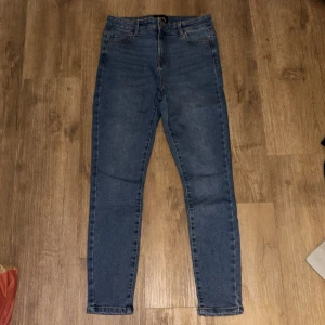 Blå skinny jeans från Pieces - Snygga blå skinny jeans från Pieces med klassisk femficksdesign och hög midja. Jeansen är tillverkade i ett stretchigt denimtyg som sitter tajt längs benen och har en enkel, stilren look. Perfekta för dig som gillar en smal siluett och bekväm passform.