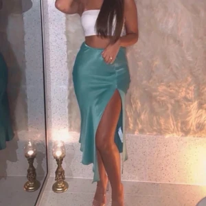 Turkos långkjol i satin med slits - Säljer en turkos långkjol i glansigt satinmaterial. Kjolen har en hög slits på sidan.