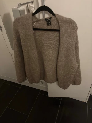 Stickad kofta Lindex  - Mysig beige stickad kofta i färgen ”light dusty brown” från Lindex och kostar 399kr ny, med öppen front och avslappnad passform. Koftan har lång ärm och är tillverkad i ett fluffigt, mjukt material som känns lyxigt och varmt. Perfekt att slänga på sig över en t-shirt eller linne💕💕💕