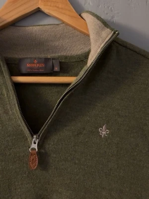 Olivgrön half zip tröja från Morris - Säljer en olivgrön långärmad tröja från Morris med half zip och snygg broderad logga på bröstet. Tröjan är i 100% merinoull och har ribbade muddar samt en stilren krage med kontrastfärg på insidan. Den är i M men passar S/xs pågrund av tvättning. Nästan aldrig använd