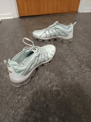 Nike Vapormax ljusblå - Använd 2 gånger men är i topp kondition. Nike Air Vapormax Plus sneakers i ljusblå färg med transparent sula och snygga detaljer. Ovandelen är i syntetmaterial med mönstrad struktur och snörning. Sulan har tydlig Air-teknologi och Nike-logga på undersidan. Perfekt för dig som gillar sportig och modern stil.