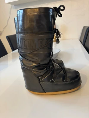 Svarta Moon Boots med snörning - Säljer ett par svarta Moon Boots med klassisk snörning och gummisula. Skorna är fodrade och perfekta för kalla dagar. Yttermaterialet är syntet och de har en hög, vadderad design som håller värmen. Snygga och ikoniska vinterboots som sticker ut, storleken 35-38 🤍 • Instagram: Ginise > tiktok: Ginise • #moonboots