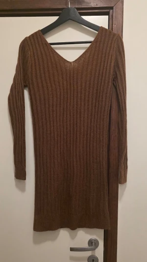 Brun ribbad stickad klänning Shein - Säljer en brun ribbad stickad klänning från Shein i storlek M. Tröjan har v-ringning, långa ärmar och en kroppsnära passform. Perfekt för lager på lager under höst och vinter. Materialet är mjukt och stretchigt för extra komfort.