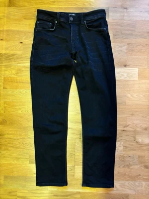 Jack & Jones Tapered/Mike w29/l30 - Säljer ett par svarta jeans från Jack & Jones - Tapered/Mike med klassisk femficksdesign och svarta sömmar. Jeansen har en tapered passform som smalnar av nedtill och är tillverkade i ett mjukt jeansmaterial. Perfekta för dig som gillar stilrena och bekväma byxor. NÄSTA OANVÄNDA.
