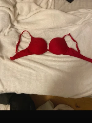 Röd BH från H&M 70B - Snygg röd BH från H&M i storlek 70B. Modellen har vadderade kupor och justerbara axelband. Den har inga tydliga täcken på slitage men ändå använd